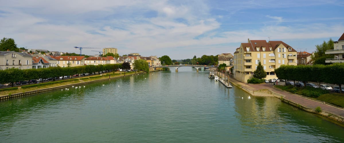 A river with a bridge, buildings, and parked cars.