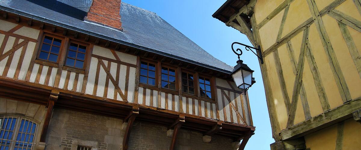 A half-timbered building with a steeply pitched roof and a visible brick chimney.