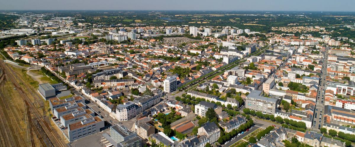 An aerial view of a city with dense urban development, a river, and surrounding greenery.