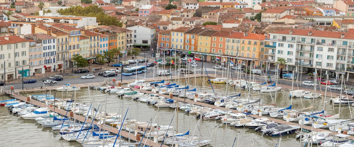 A marina filled with boats, surrounded by colorful buildings and a busy street.