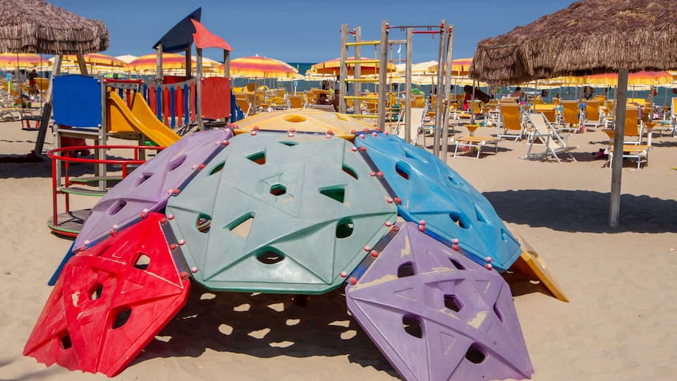 A beach play area with colorful climbing structures and thatched umbrellas.