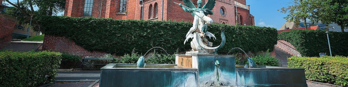 A historic church with a tall spire and a statue of an angel in the foreground.