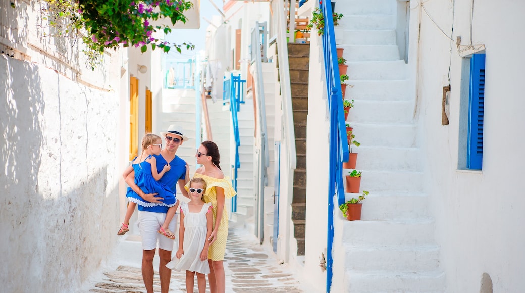 Family vacation in small european city. Parents and kids at street of greek traditional village on Mykonos Island