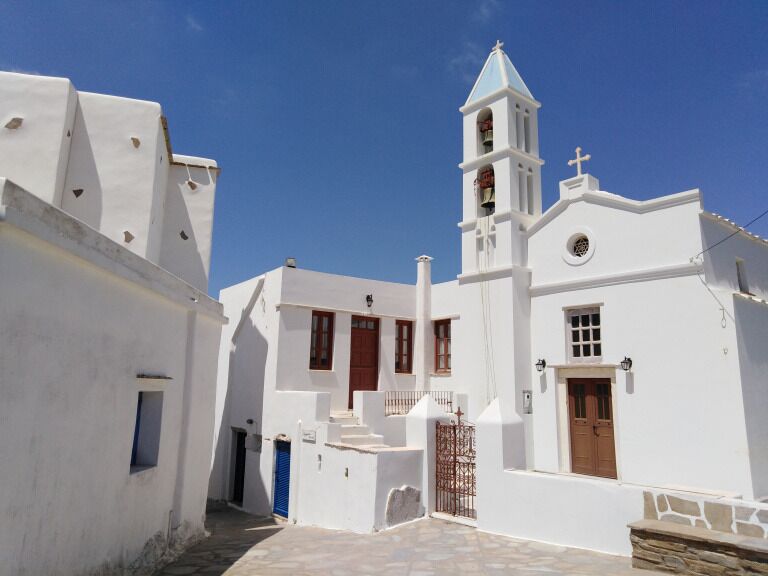 A white church with a bell tower and blue doors.