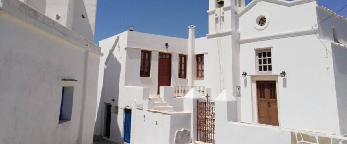 A white church with a bell tower and blue doors.