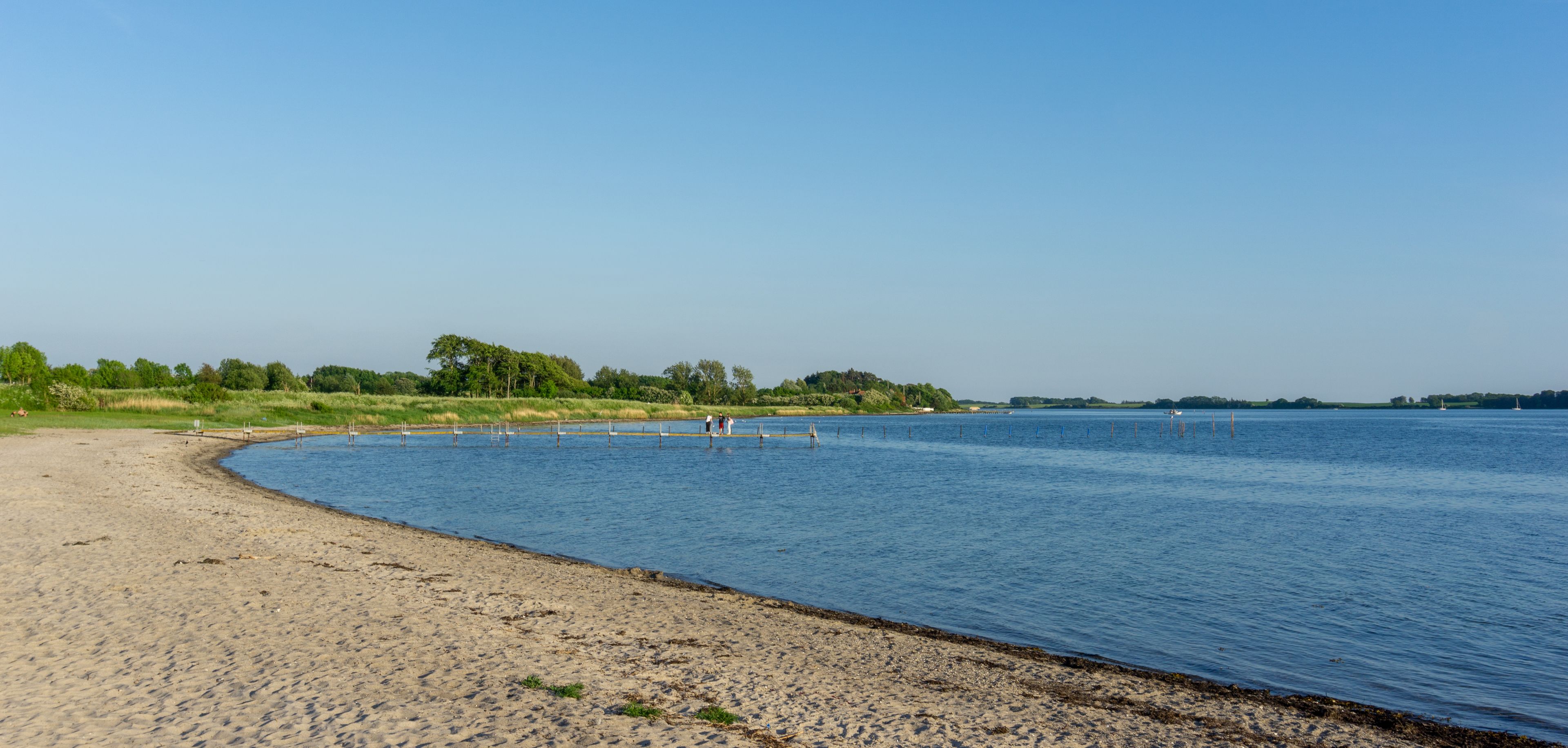 tourists enjoy an evening on the pier and beach at Middelfart harbor