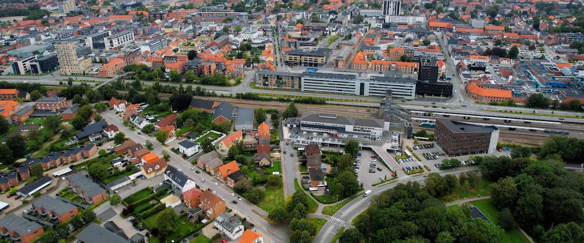 An aerial view of a city with dense residential areas, a prominent train station, and a large industrial complex.