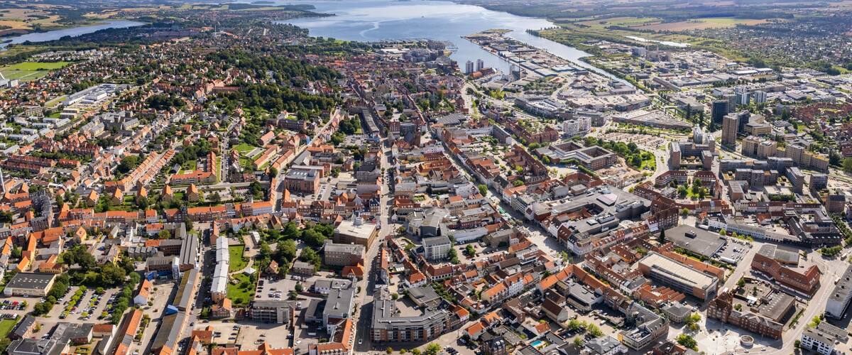 An aerial view of a city with a river, dense residential areas, and a mix of modern and historic buildings.