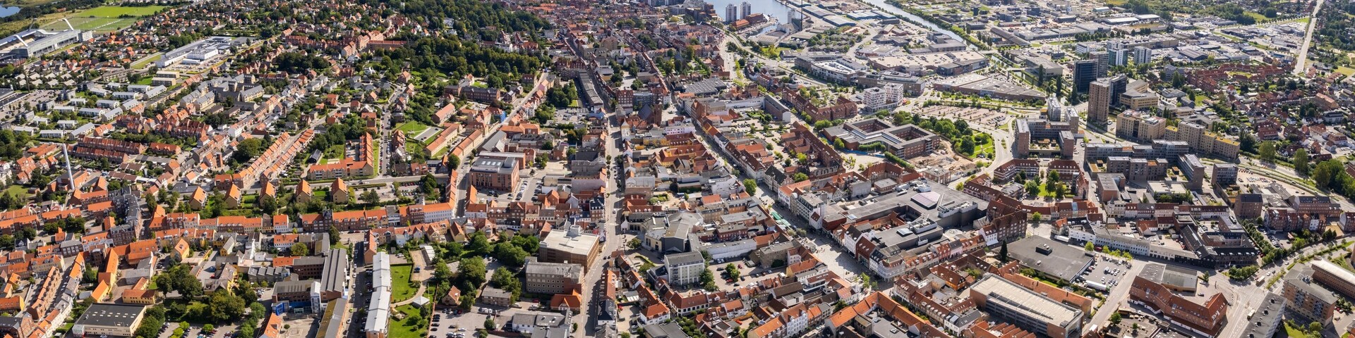 An aerial view of a city with a river, dense residential areas, and a mix of modern and historic buildings.