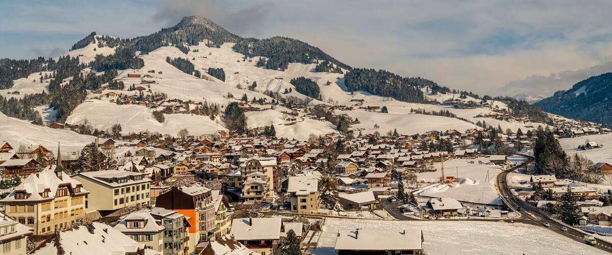 A snow-covered mountain town with buildings and a winding road.