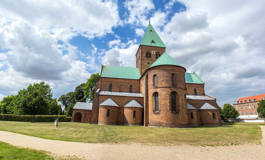 Historiallinen kirkko, jossa on vihreä torni ja tiilestä rakennettu julkisivu.