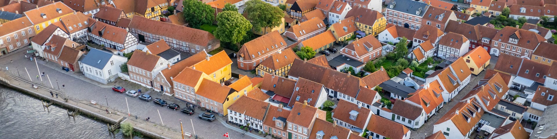 A historic town with a prominent church, a river with boats, and a dense cluster of traditional buildings.