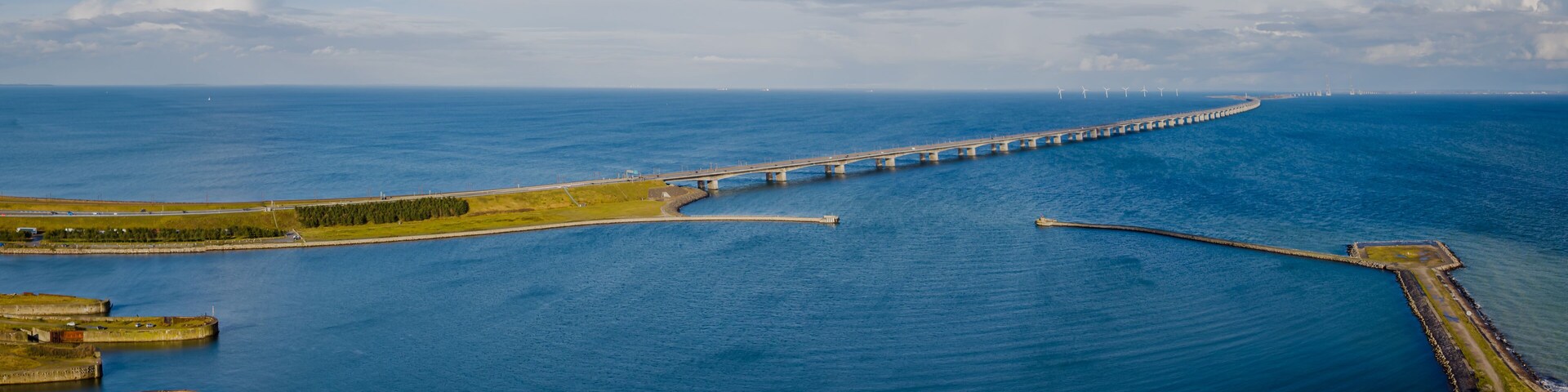 View from the coast of the island of Fyn, where the Storebælt Bridge spans across the horizon, seamlessly connecting two picturesque coasts. Scenic transportation network on the Great Belt Bridge.