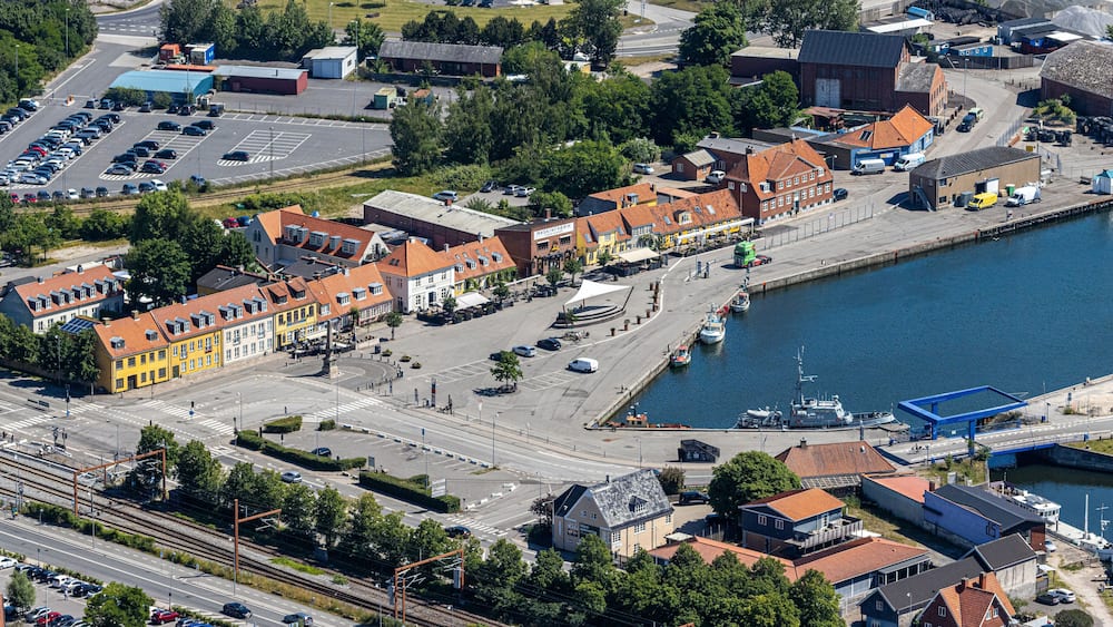 Eine Vogelperspektive einer Küstenstadt mit einem Yachthafen, bunten Gebäuden und einer Eisenbahnlinie.