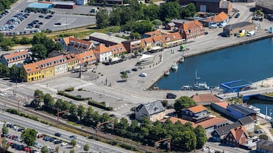 An aerial view of a coastal town with a marina, colorful buildings, and a railway line.