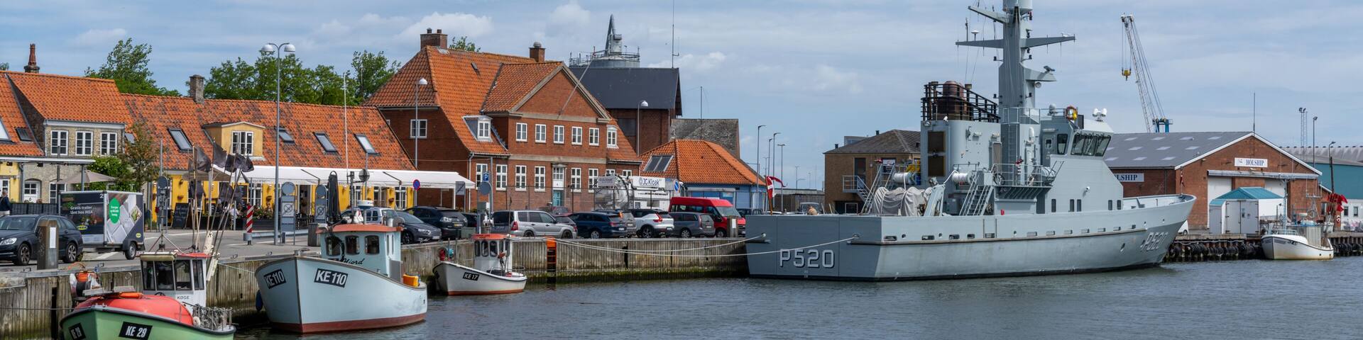 the harbor and port of Koge with colorful boats and a warship from the Danish navy