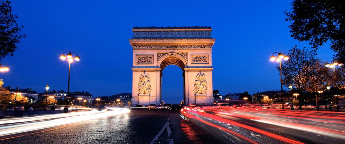 The Arc de Triomphe at night with light trails from traffic.