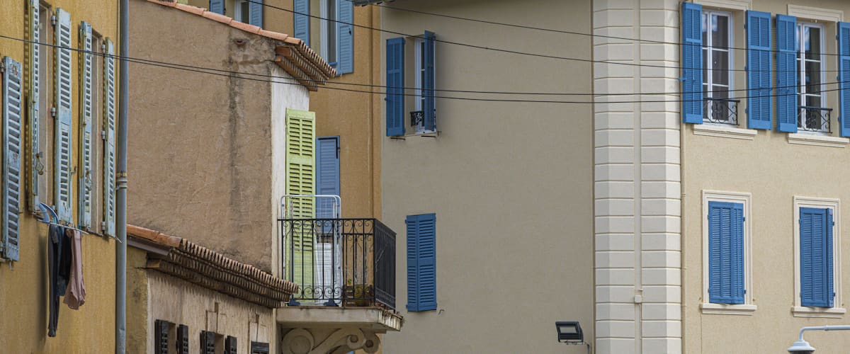 A row of buildings with blue shutters and a street lamp.