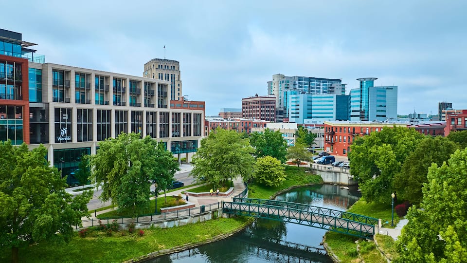 A cityscape with modern buildings, a river, and a bridge.