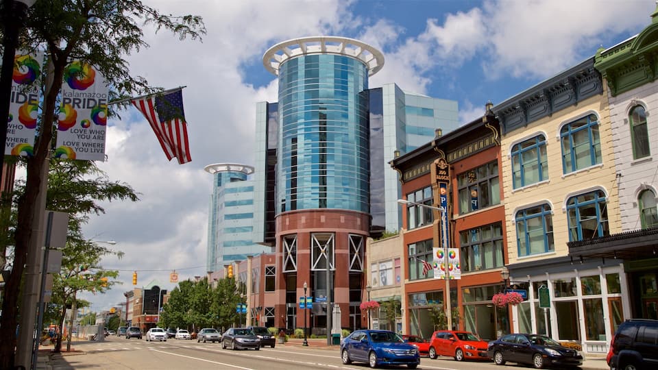 A city street with modern buildings, cars, and flags.