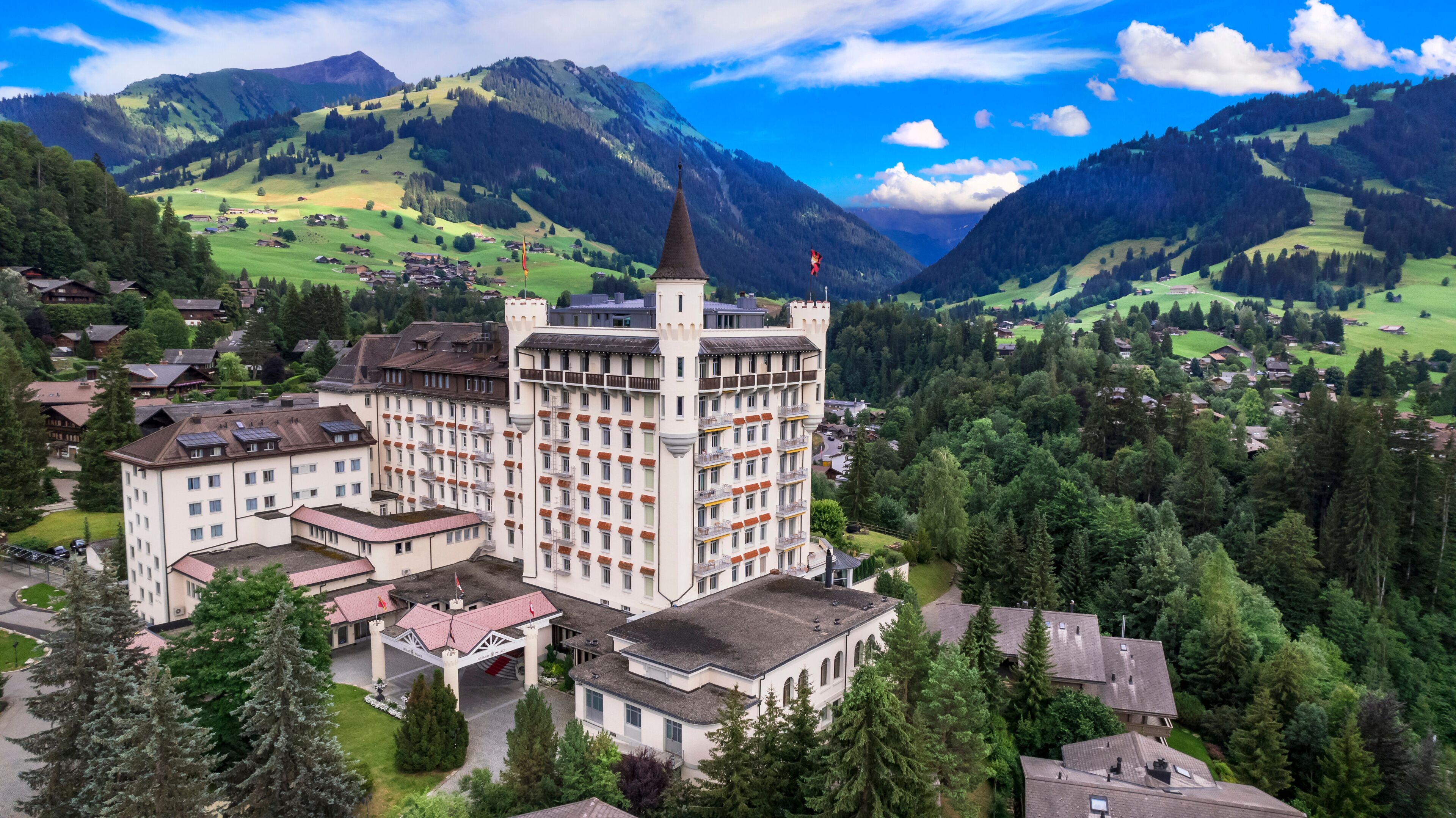 Castle hotel among green hills and mountains, Gstaad, Saanen, Bernese Oberland, Switzerland Aerial luxury alpine landscape. World print quality, High end slow travel