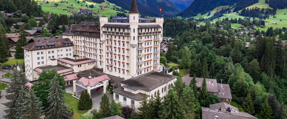 Castle hotel among green hills and mountains, Gstaad, Saanen, Bernese Oberland, Switzerland Aerial luxury alpine landscape. World print quality, High end slow travel