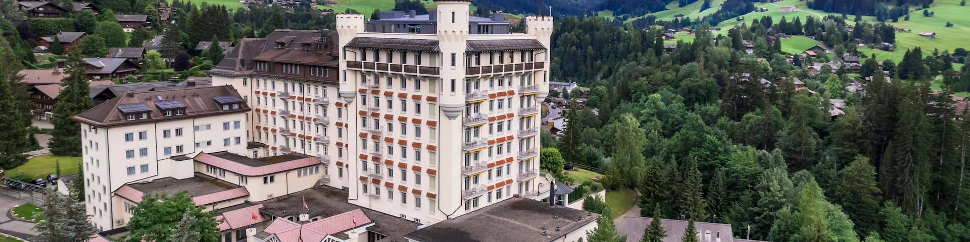 Castle hotel among green hills and mountains, Gstaad, Saanen, Bernese Oberland, Switzerland Aerial luxury alpine landscape. World print quality, High end slow travel