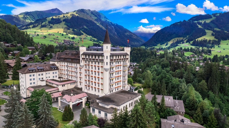 Castle hotel among green hills and mountains, Gstaad, Saanen, Bernese Oberland, Switzerland Aerial luxury alpine landscape. World print quality, High end slow travel