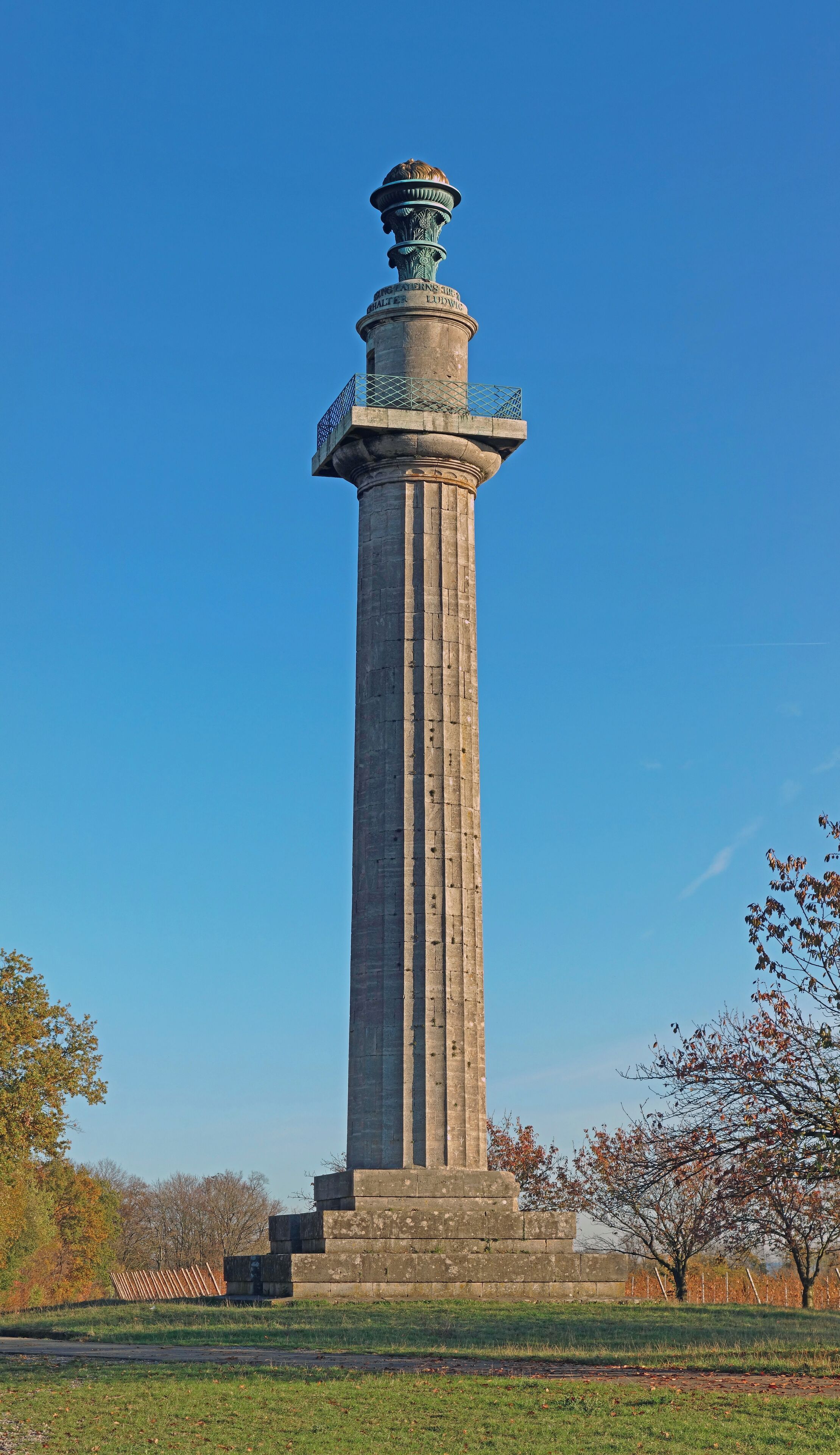 A tall, ornate monument with a weathered stone base and a decorative top.