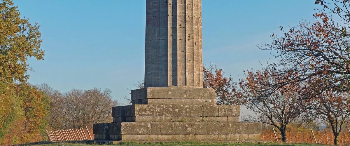 A tall, ornate monument with a weathered stone base and a decorative top.