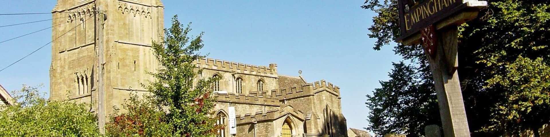 A church with a tall spire and a sign for 'The King's Arms' pub.
