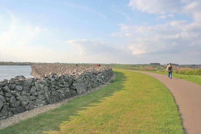 A paved path alongside a stone wall by the water.