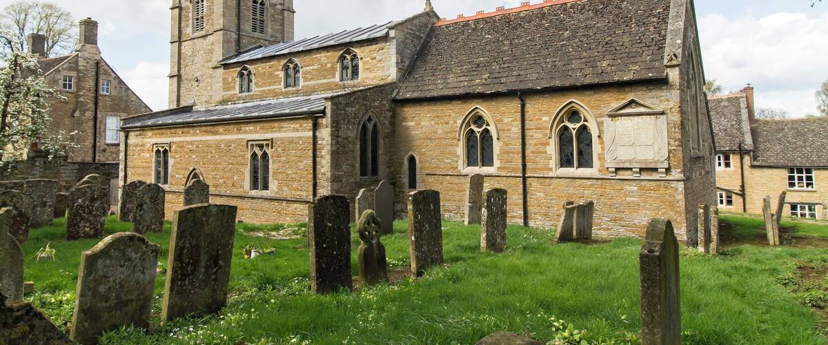 A historic church with a tower and a graveyard in front.