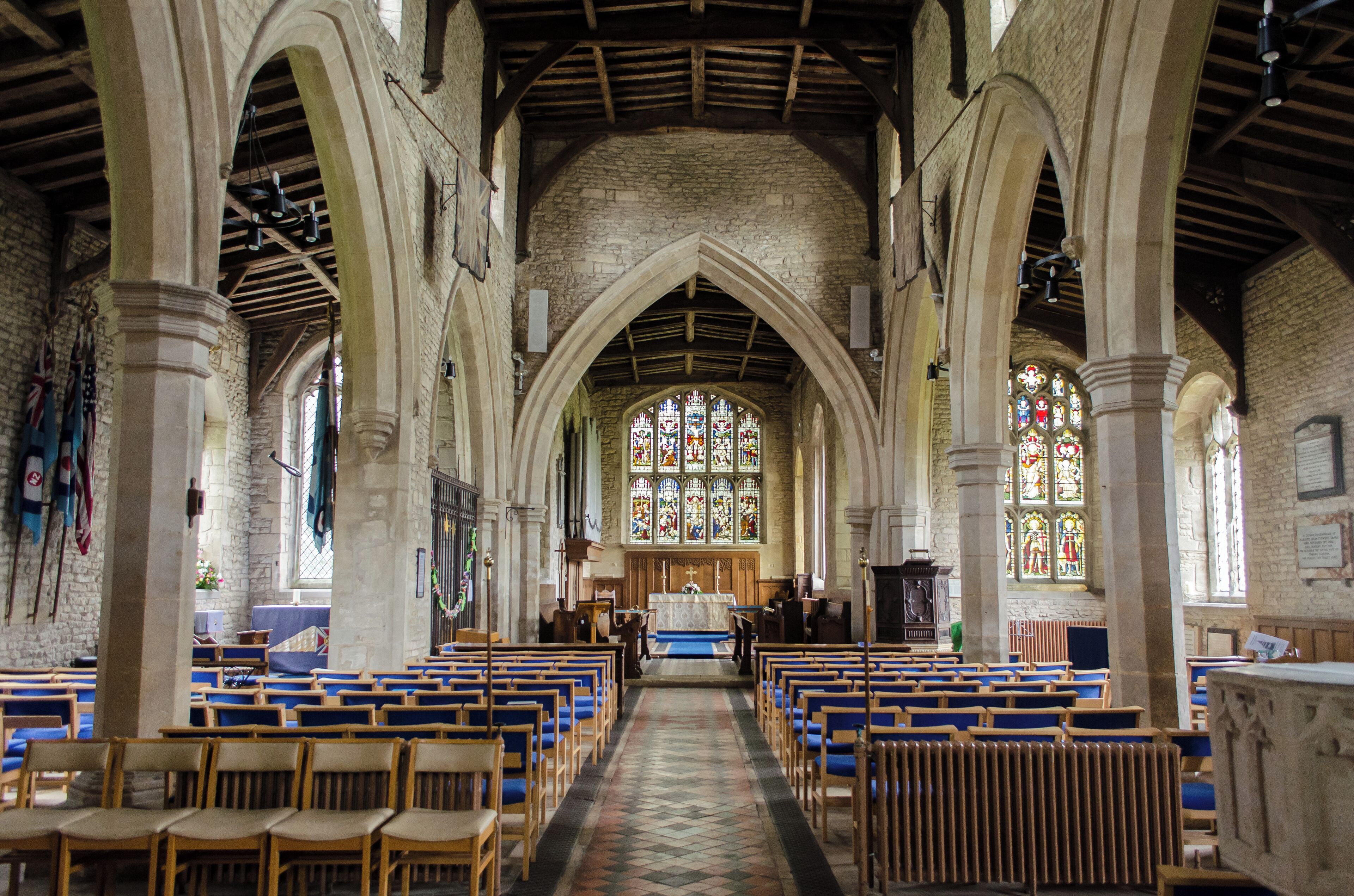A church interior with arched ceilings, stained glass windows, and wooden pews.