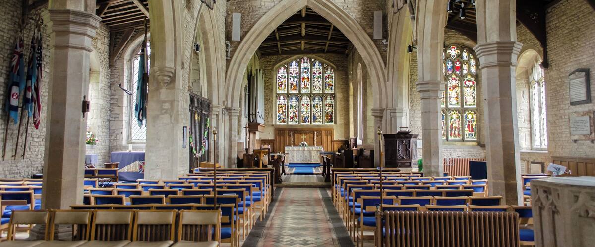 A church interior with arched ceilings, stained glass windows, and wooden pews.