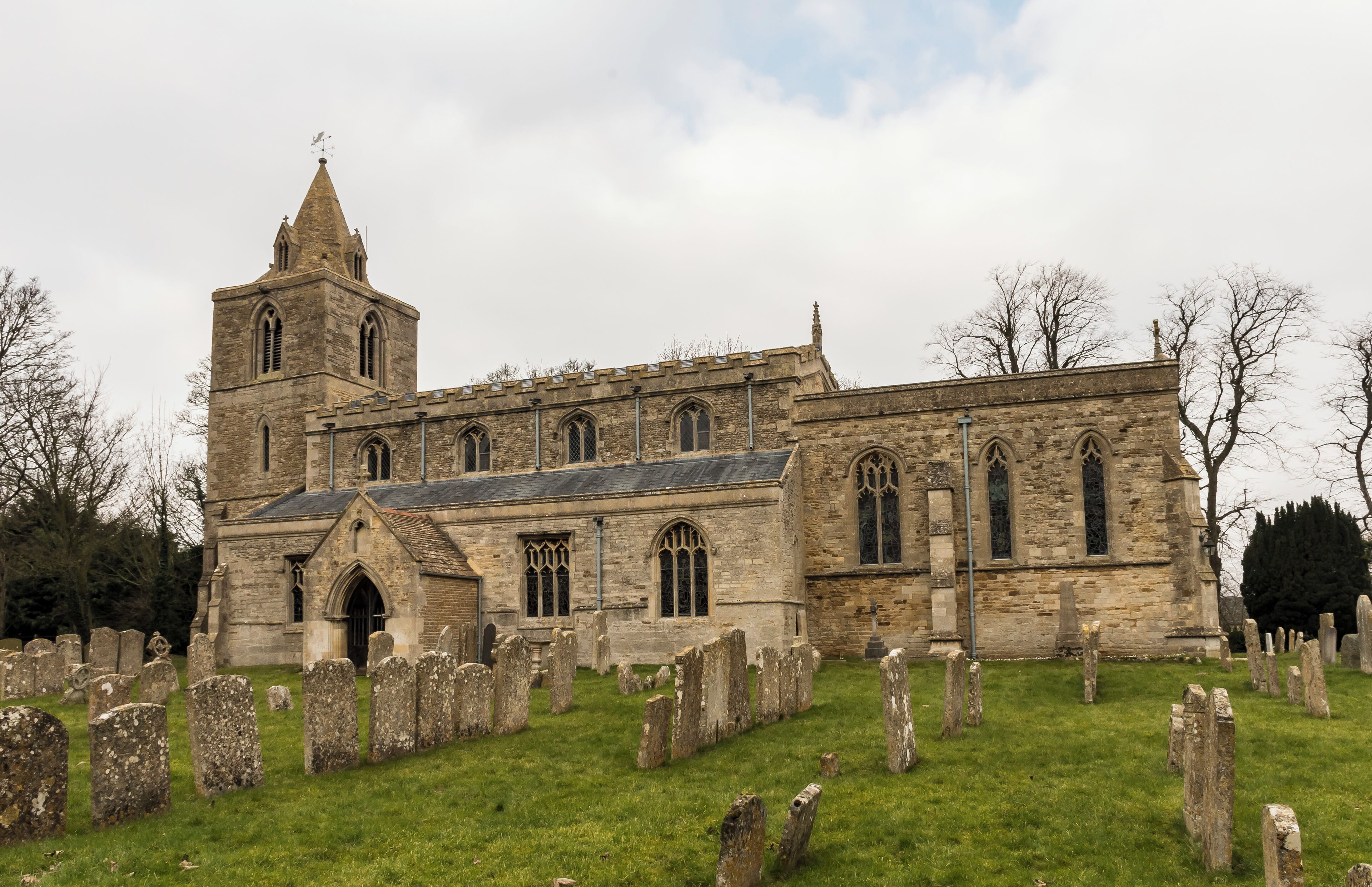 A historic church with a prominent tower and a graveyard in front.