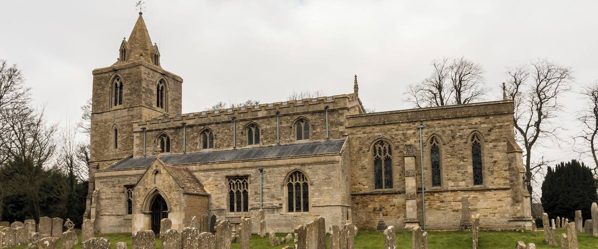 A historic church with a prominent tower and a graveyard in front.