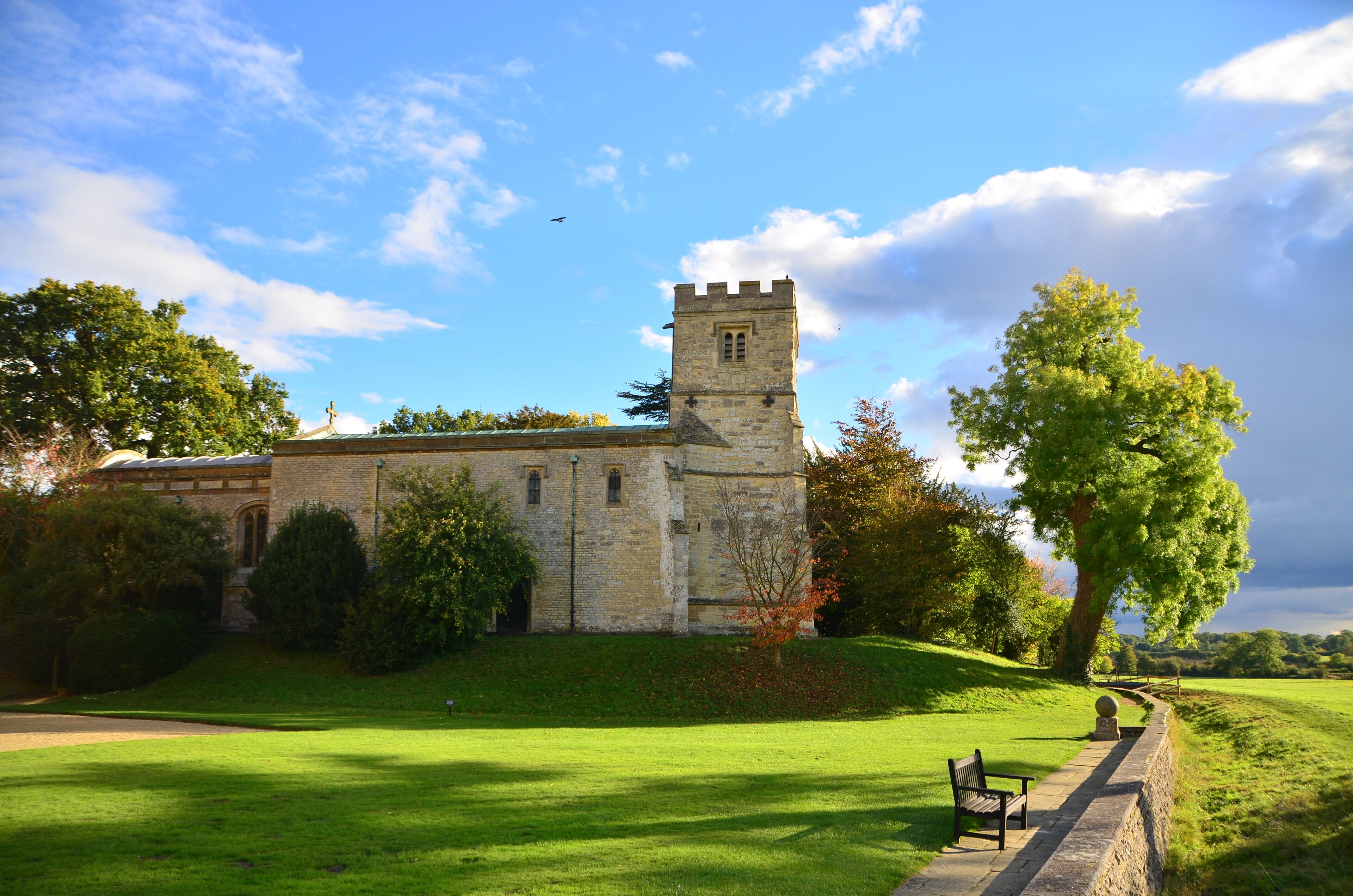 A historic stone building with a tower, surrounded by lush green grass and trees.