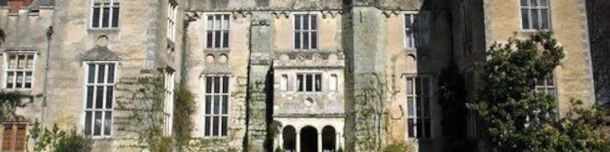 Ein historisches Steinhaus mit einer symmetrischen Fassade, Rundbogenfenstern und einem zentralen Innenhof mit einem Brunnen.