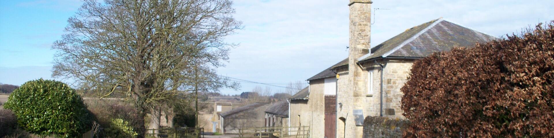 A rural path leading to stone buildings with a wooden gate.