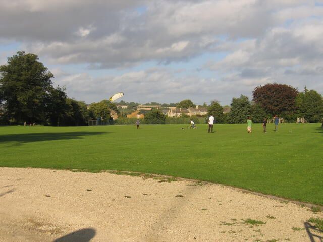 A grassy field with a kite flying in the sky.