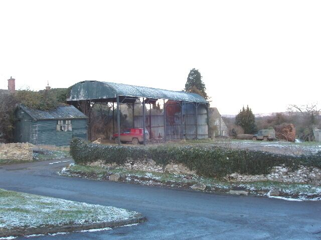 A rural landscape with a metal shed, a red car, and a river.