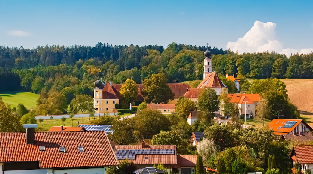 Ein Dorf mit traditioneller Architektur, eine Kirche mit Kirchturm und Solaranlagen auf den DĂ€chern.