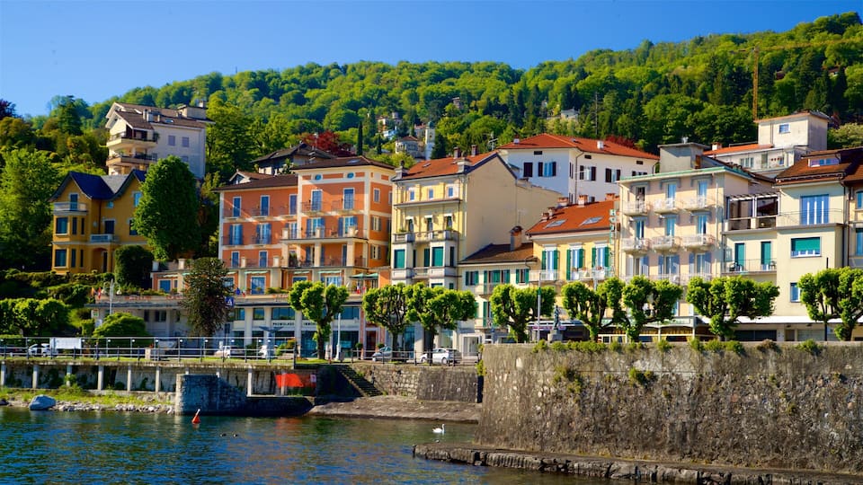 A waterfront town with colorful buildings, a river, and a forested hillside.