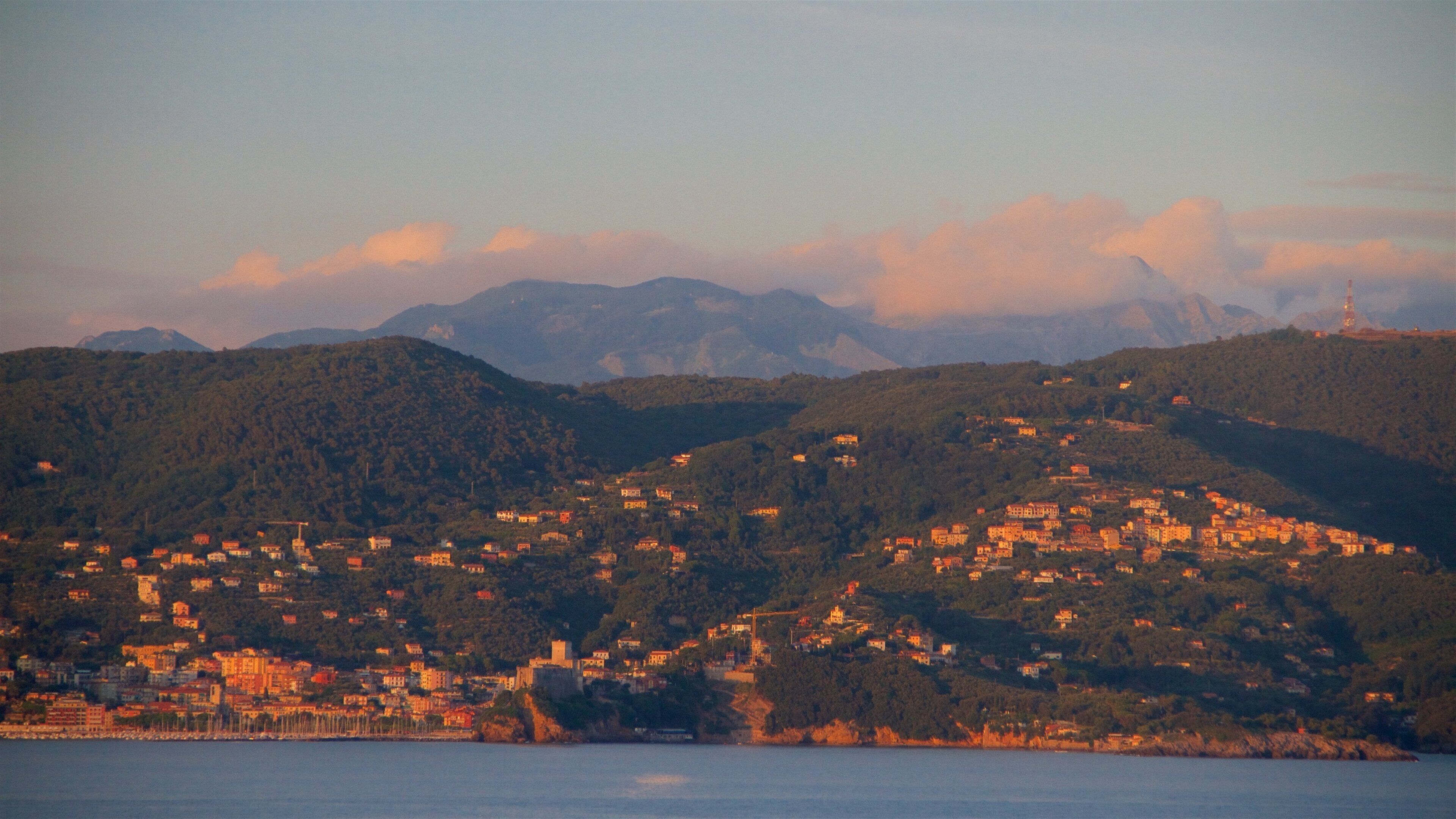 A coastal town nestled in a valley with mountains in the background.