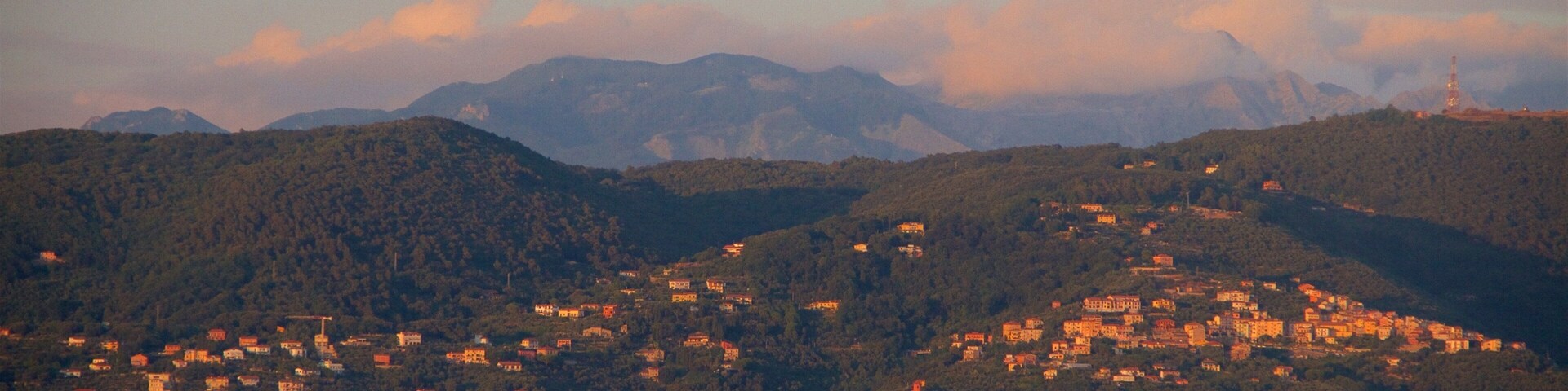 A coastal town nestled in a valley with mountains in the background.