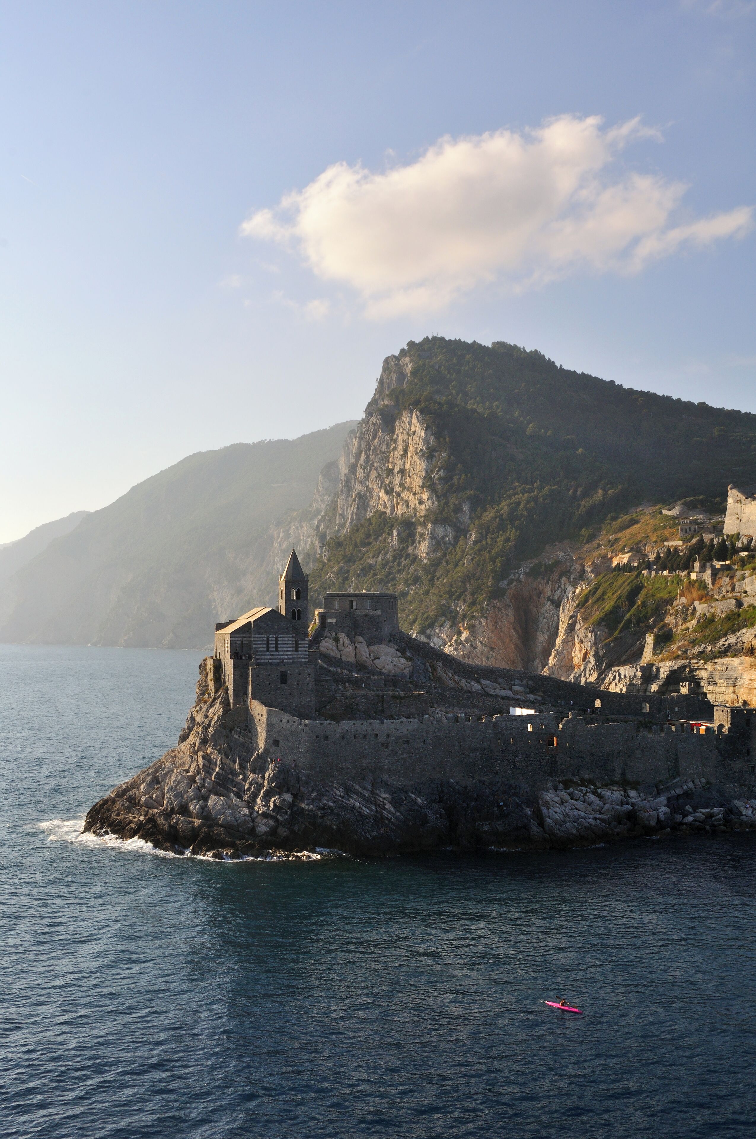 A coastal town with a prominent church on a cliff, rocky coastline, and a clear sky.