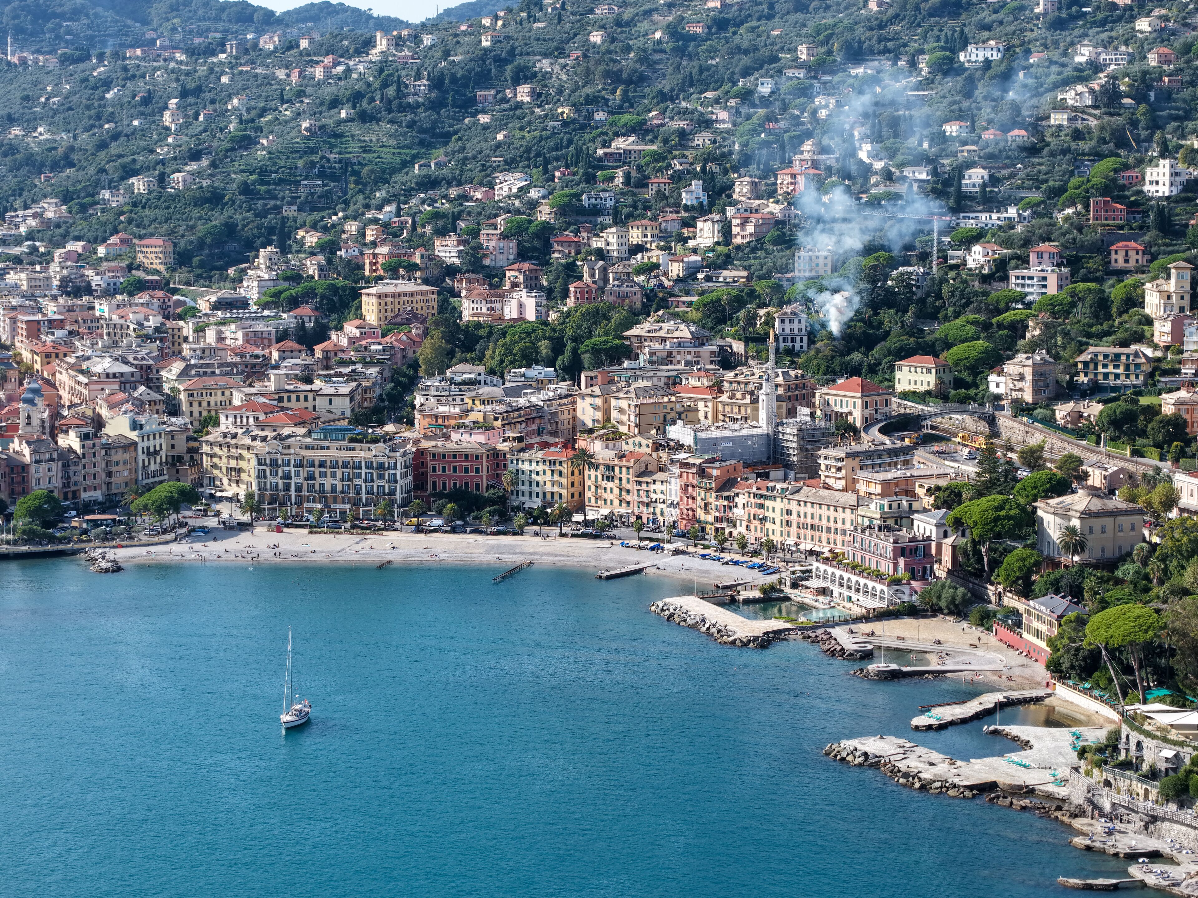 A coastal cityscape with a prominent church, a beach, and a marina.