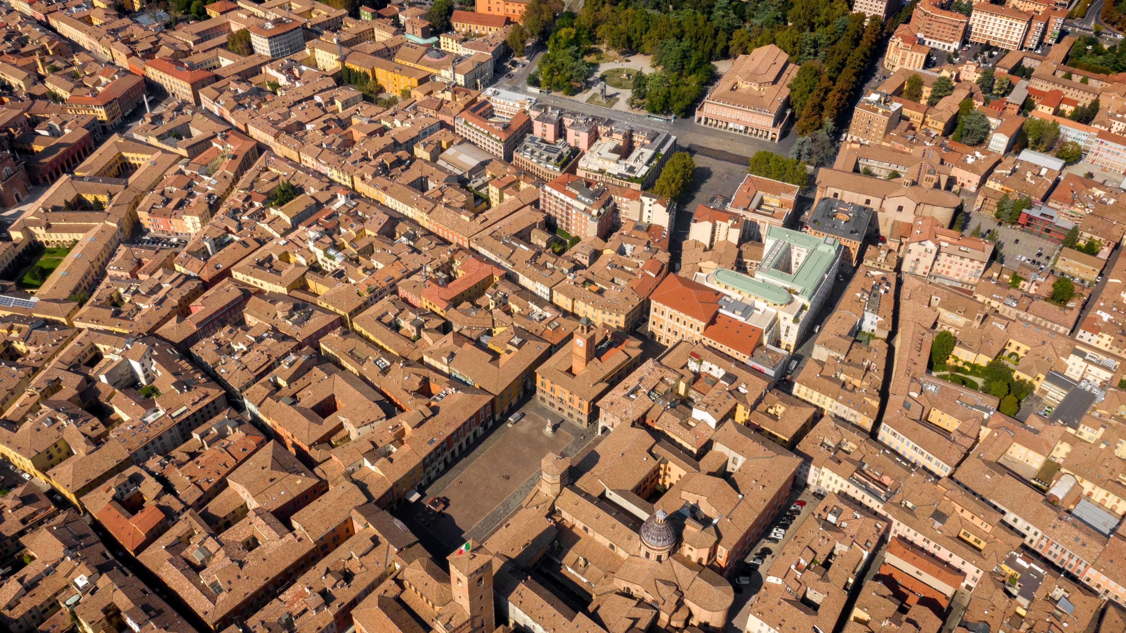 An aerial view of a densely packed urban area with historic buildings, a prominent church with a dome, and a large green-roofed building.