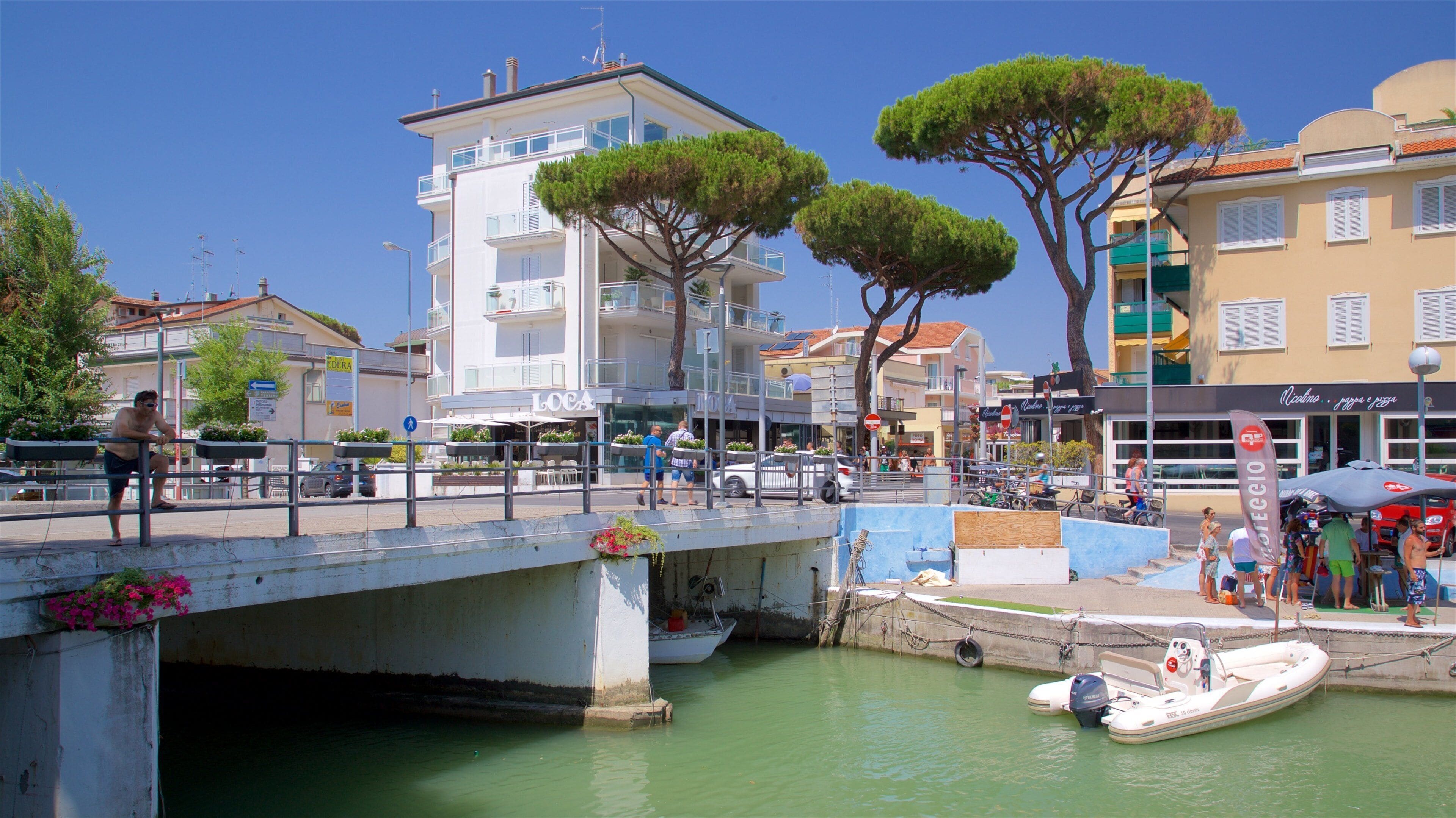 A waterfront promenade with a bridge, boats, and buildings.
